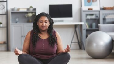 a woman sitting in a yoga position with her eyes closed