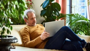 a man sitting on a couch using a laptop computer