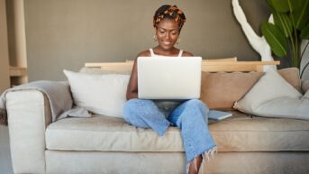 a woman sitting on a couch using a laptop computer