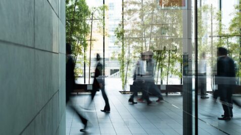 people are walking in the lobby of an office building