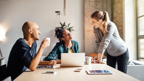 three people sitting at a table having a conversation