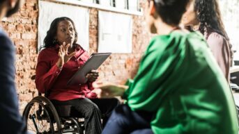 a woman in a wheel chair talking to another woman