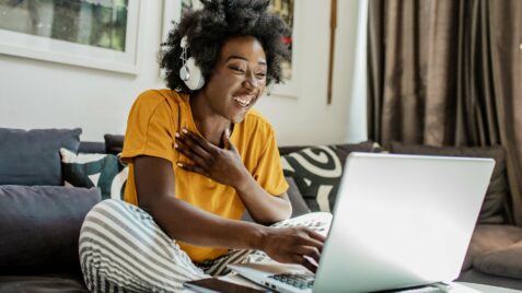 a woman sitting on a couch using a laptop computer