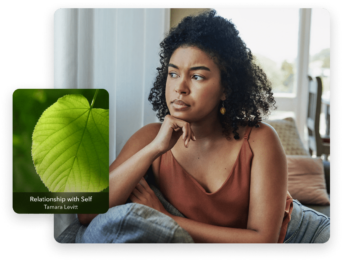 a woman sitting on a couch next to a green leaf