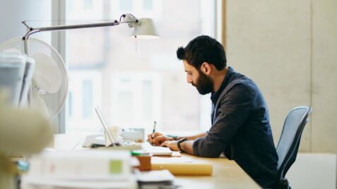 a man sitting at a desk with a laptop