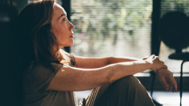 a woman sitting on a chair looking out a window