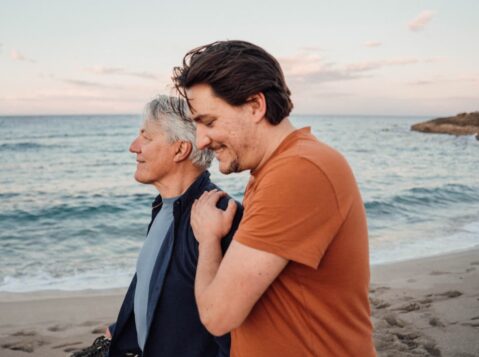 a couple of men standing next to each other on a beach