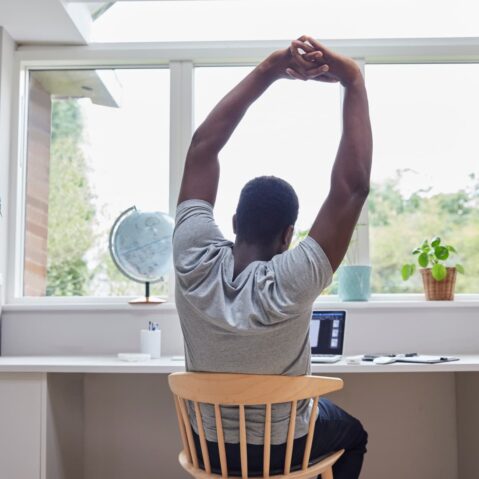 a man sitting at a desk with his arms in the air