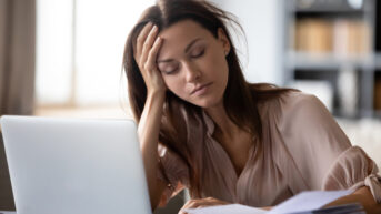 a woman with chronic pain sitting at desk with laptop