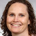 a woman with curly hair is smiling at the camera