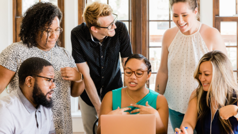 a group of people gathered around a laptop