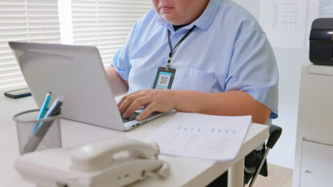 a man sitting at a desk using a laptop computer