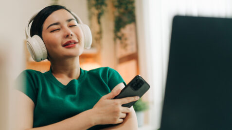 a woman wearing headphones and holding a remote control