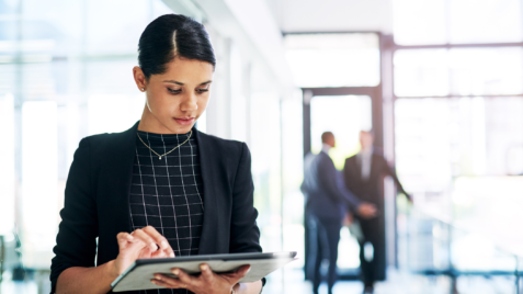 a woman standing in a lobby using a tablet