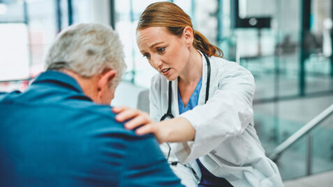 Female doctor having a consultation with her elderly patient, possibly experiencing compassion fatigue